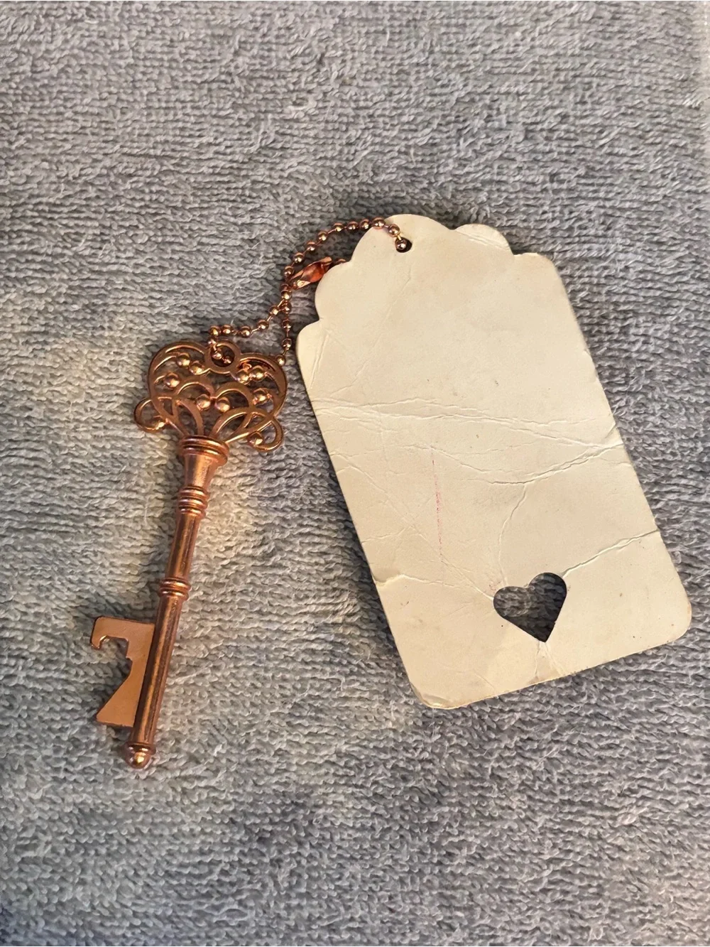 Gold tone Key-shaped pendant with card.